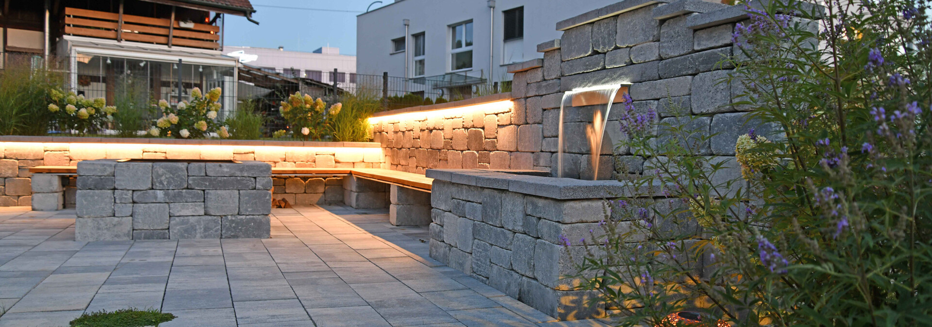 Sichtschutzmauer mit gemütlicher Grillstelle und Edelstahl-Wasserbecken